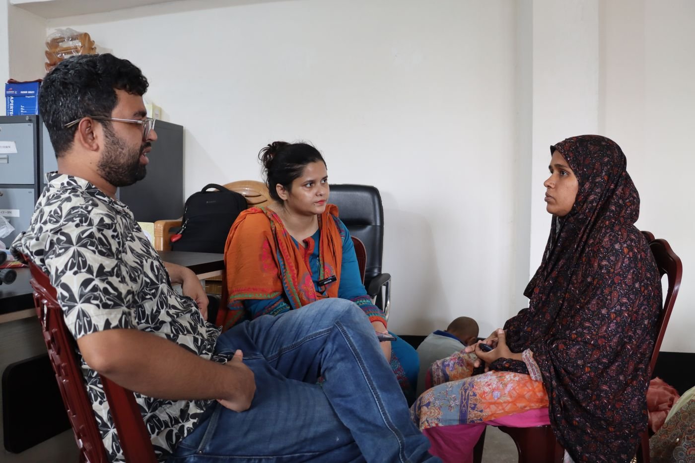 Two researchers sitting with a maker during a check-in conversation